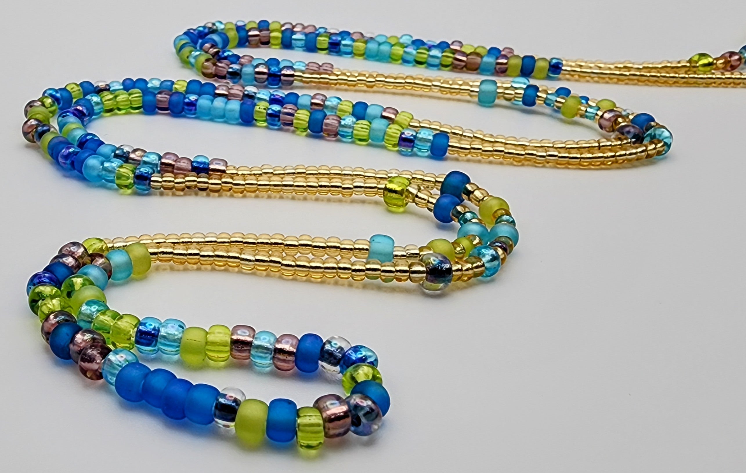 Waist beads made of beads in alternating patterns, featuring green, purple, blue, and gold beads.
