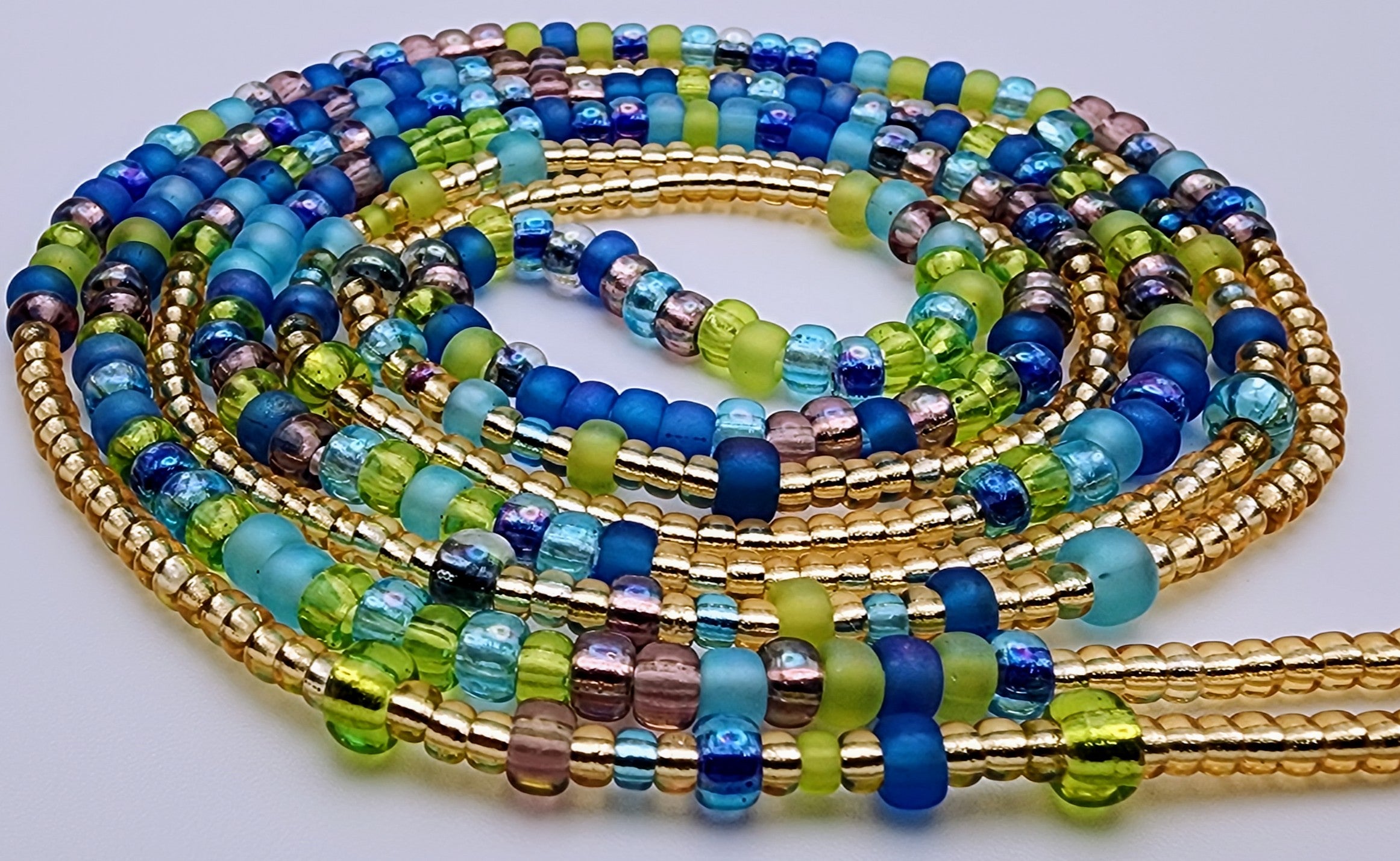 Waist beads made of beads in alternating patterns, featuring green, purple, blue, and gold beads.