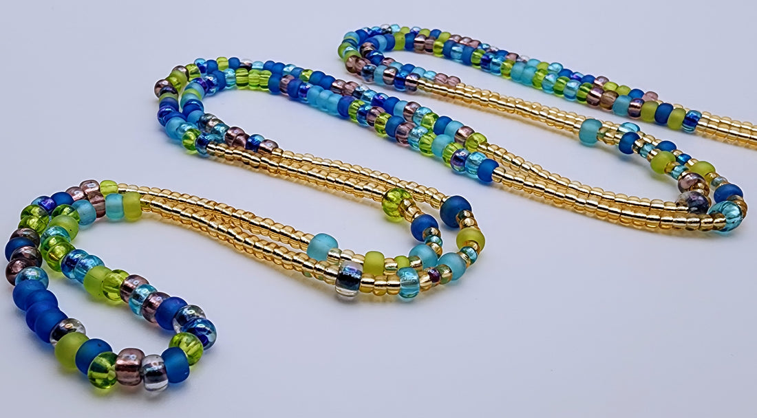 Waist beads made of beads in alternating patterns, featuring green, purple, blue, and gold beads.